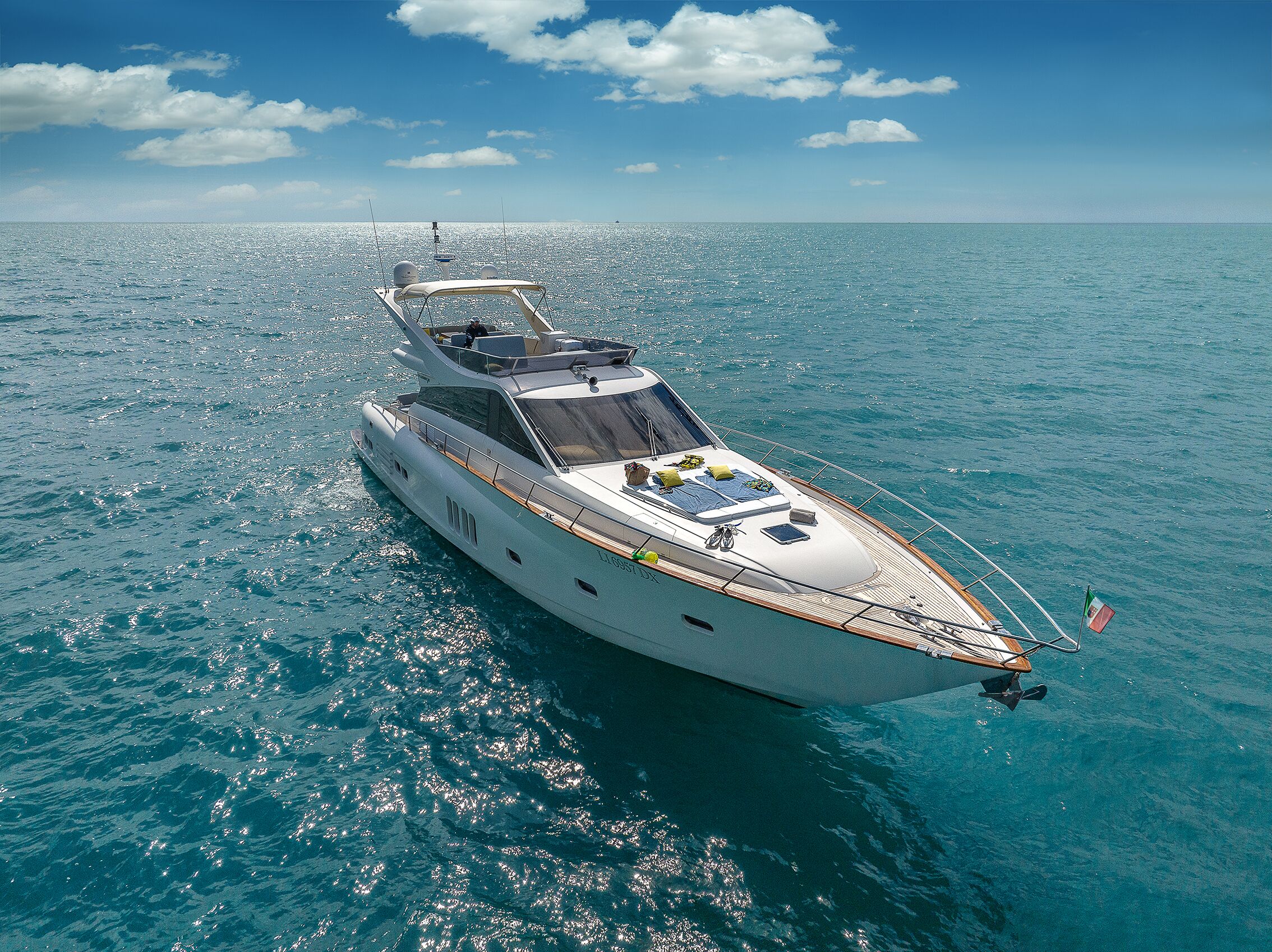 A large yacht with a spacious deck, multiple seating areas, and a flag.