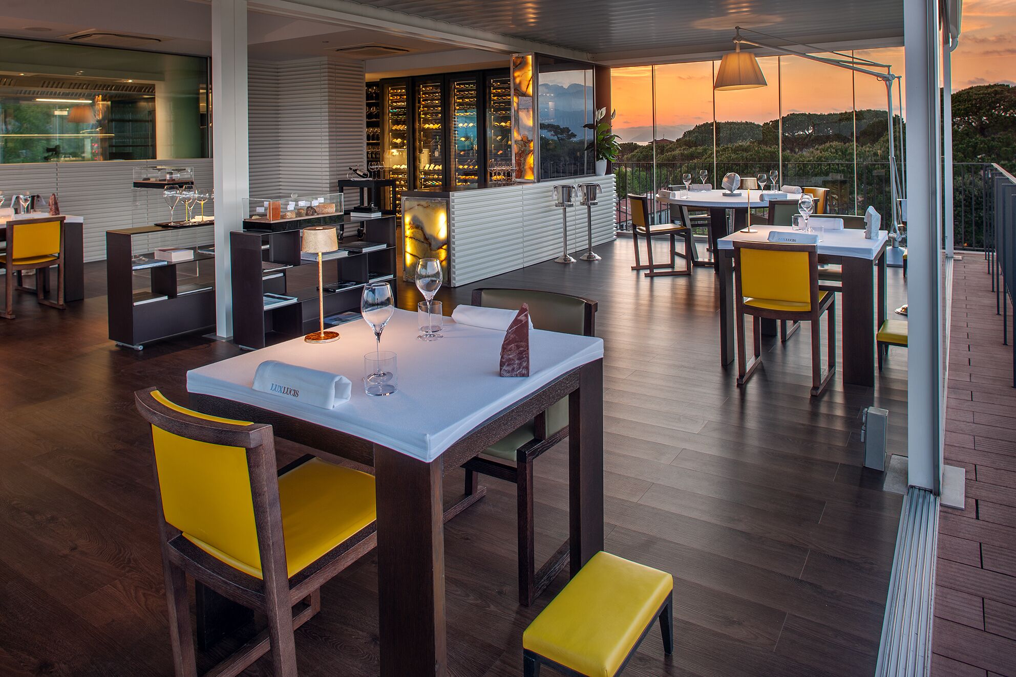 Un ristorante con terrazza, pavimento in legno e sedie gialle.