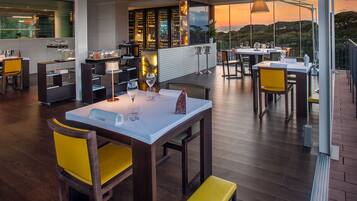 Un ristorante con terrazza, pavimento in legno e sedie gialle.