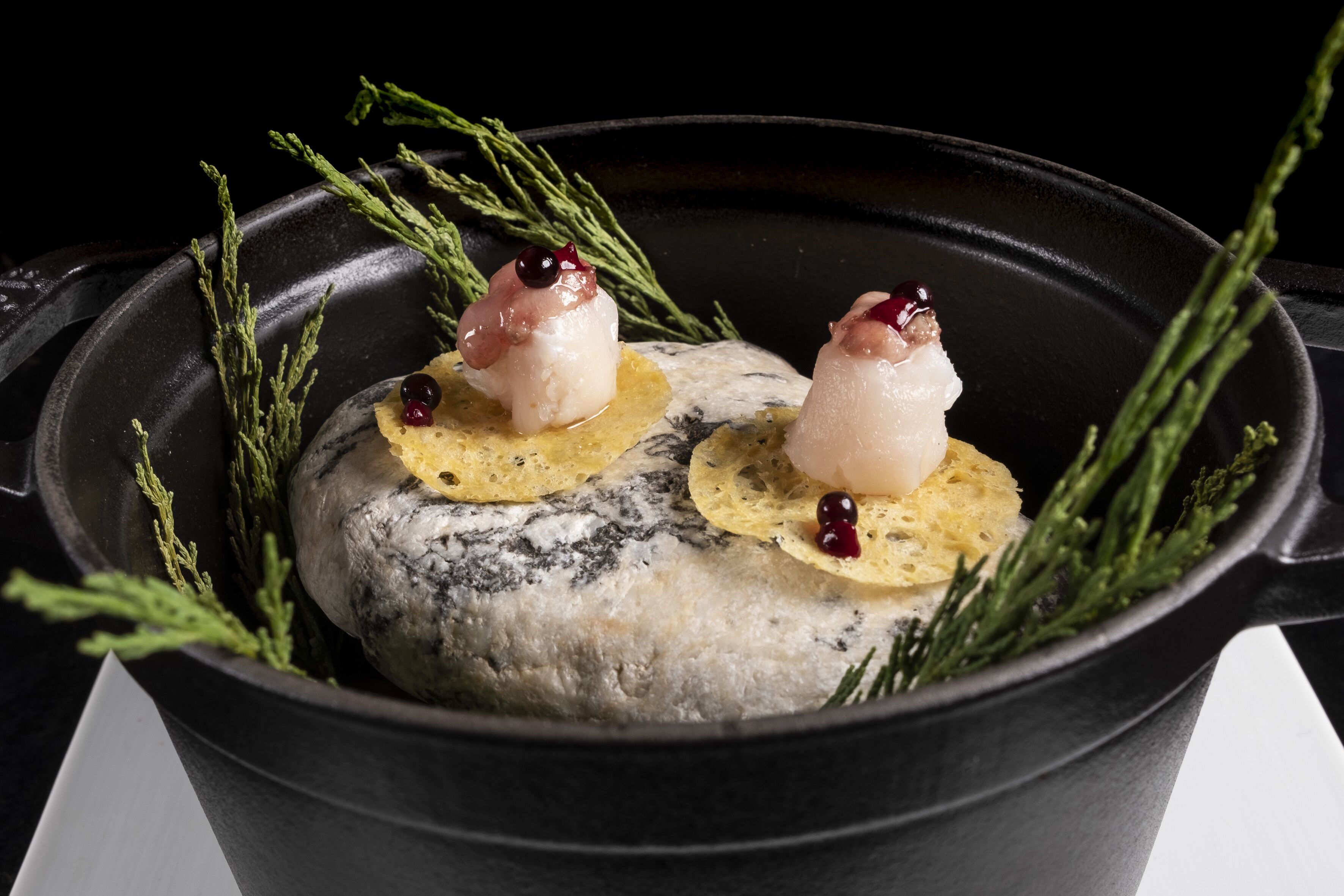Un plat de poisson, agrémenté de garnitures et d’herbes, servi dans un récipient noir.