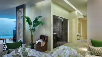 Habitación de hotel moderna con una planta en maceta grande, un sofá con cojines estampados y vistas al océano.