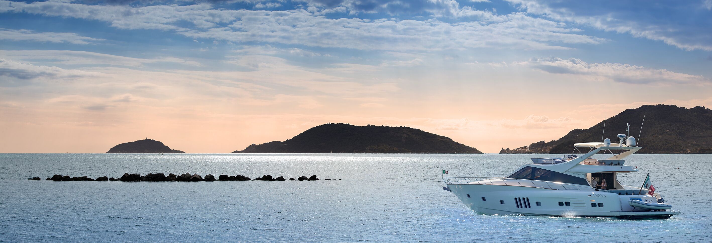 Uno yacht su acque calme con montagne sullo sfondo.