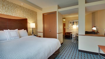 A hotel room with a large bed, a desk, a chair, and a small table.