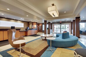 Eine moderne Lobby mit einer Rezeption, einer Sitzecke und großen Fenstern.