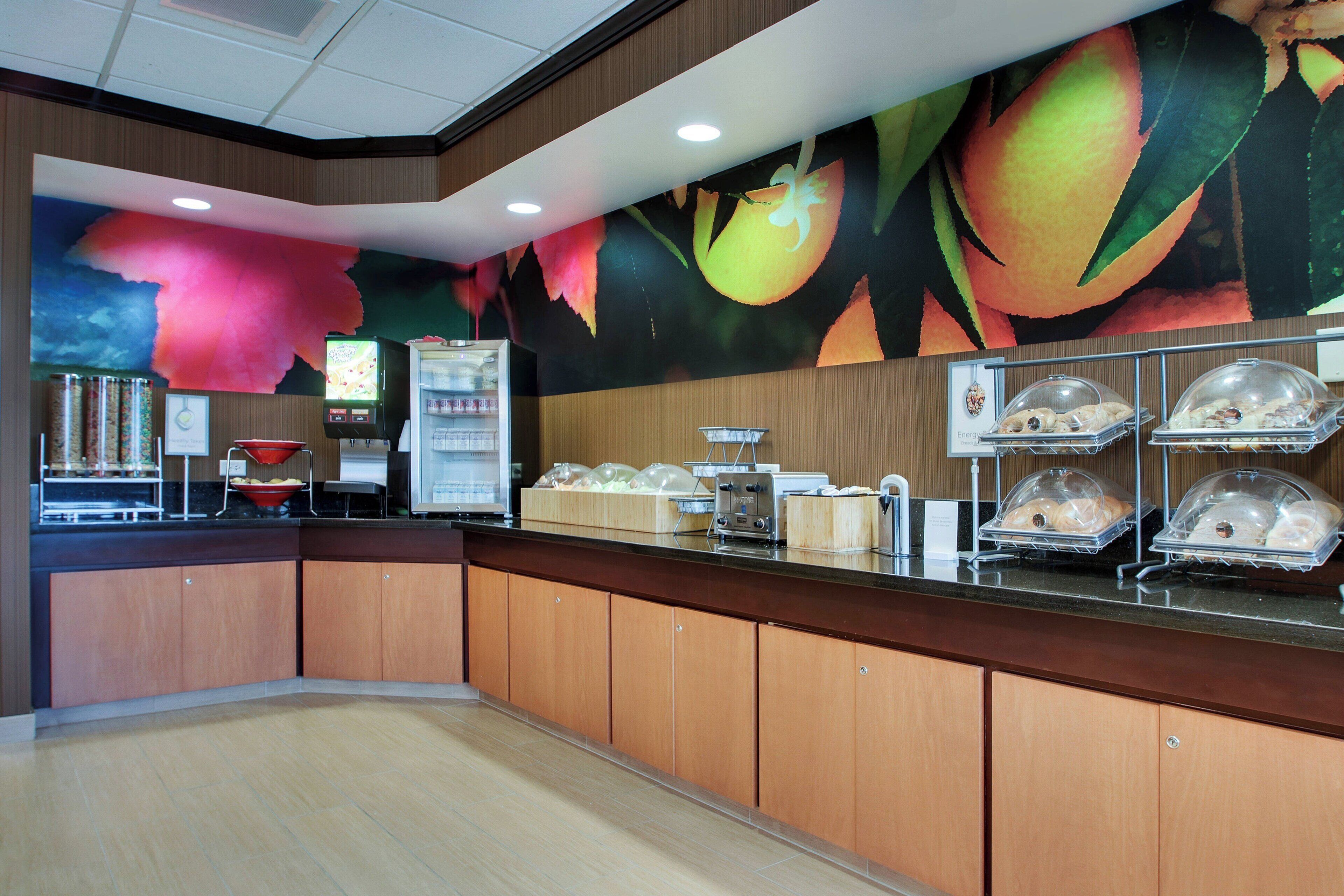 A breakfast area with a counter, a refrigerator, a microwave, and a fruit display.