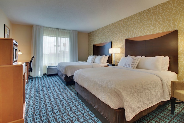 A hotel room with two beds, a desk, and a wardrobe.