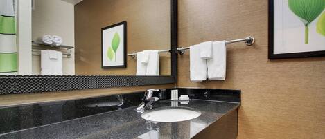 A modern bathroom with a black granite sink, a large mirror, and framed artwork on the walls.