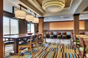 Ein Speisesaal eines Hotels mit einem großen Tisch, mehreren Stühlen und einem gemusterten Teppich.