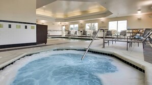 Une piscine intérieure dotée d’un jacuzzi, de chaises longues et d’un panneau indiquant qu’il est interdit de plonger.