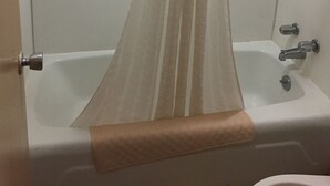 A bathroom with a bathtub, a shower curtain, and a towel rack. - Budget Inn And Suites (Abbeville)
