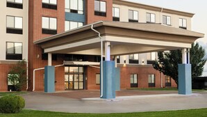 A Holiday Inn Express & Suites building with a covered entrance and a brick facade. - Holiday Inn Express Hotel & Suites Pratt by IHG (Pratt)