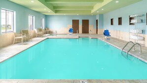 A swimming pool with lounge chairs, a changing room, and a towel rack. - Holiday Inn Express Hotel & Suites Pratt by IHG (Pratt)