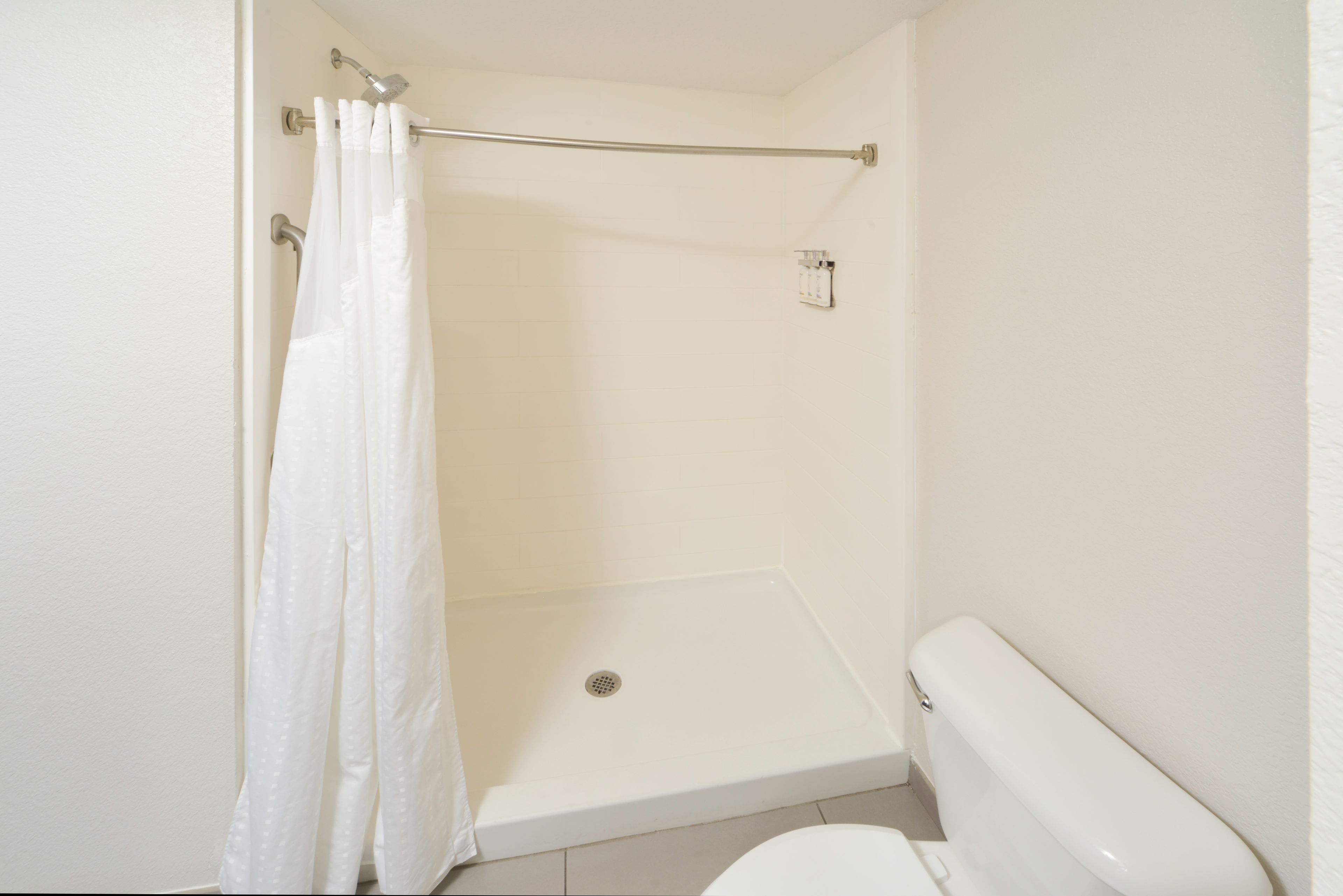 A bathroom with a shower, toilet, and a towel rack.