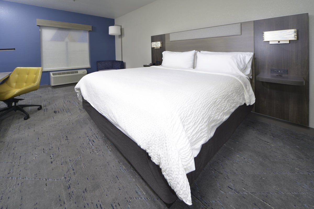 A modern hotel room with a large bed, a desk, and a chair.