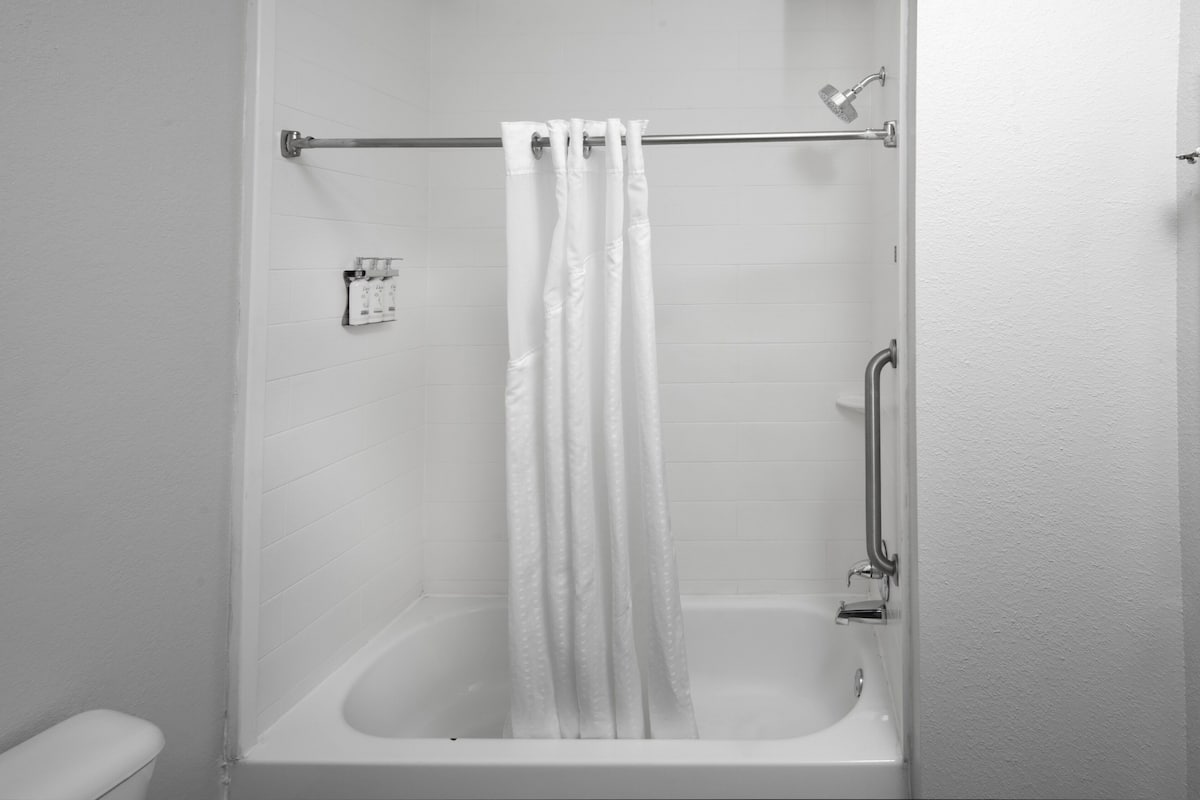 A standard white bathroom with a bathtub, a toilet, and a shower area.