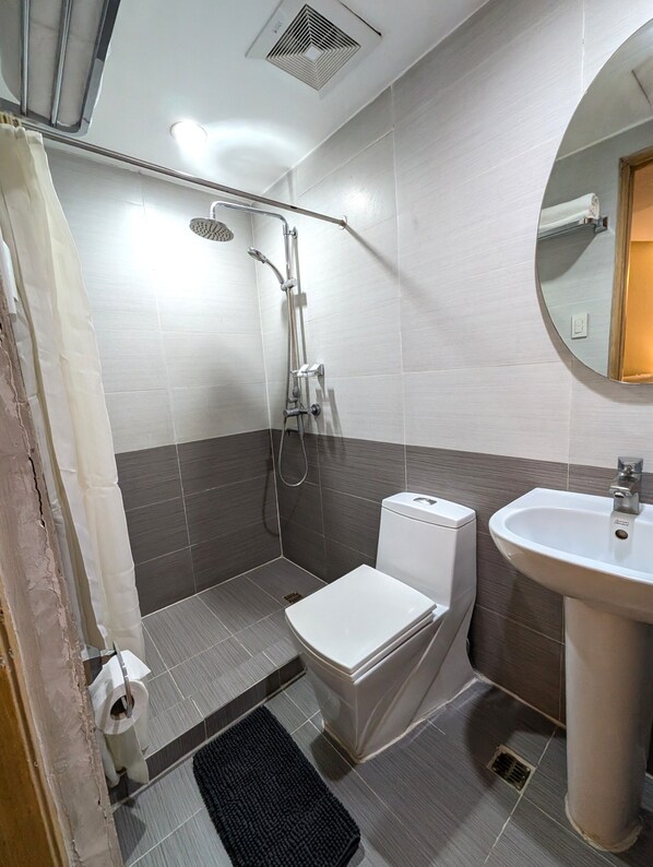 Ein Badezimmer mit Dusche, Toilette, Waschbecken und Spiegel.