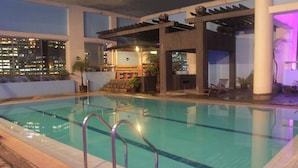 An indoor swimming pool with clear water, metal railings, and a cityscape view in the background. - Prince Plaza II Hotel (Makati)