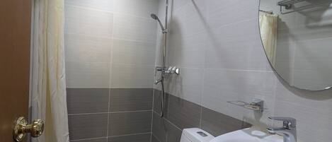 Ein Badezimmer mit Dusche, Toilette, Waschbecken und Spiegel.