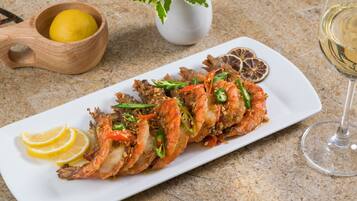 A seafood dish on a white plate with lemon slices and a glass of white wine.