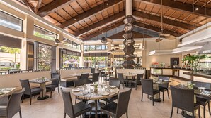 A spacious indoor dining area with high ceilings and natural light, featuring multiple dining tables and chairs. - Henann Garden Resort (Boracay Island)