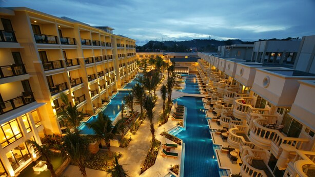 A hotel with multiple floors, a central swimming pool, and outdoor seating areas. - Henann Garden Resort (Boracay Island)