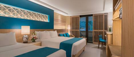 A hotel room with two beds, a desk, and a view of the outdoors.