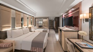 A modern hotel room with a large bed, a desk with a flat-screen TV, a vanity with a mirror, and a bathroom visible through an open door. - Henann Garden Resort (Boracay Island)