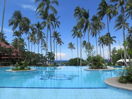A swimming pool surrounded by tall palm trees and a clear blue sky.