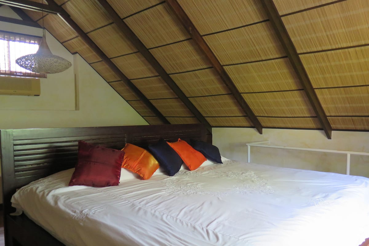 A bed with a wooden headboard, white bedding, and several pillows in various colors.
