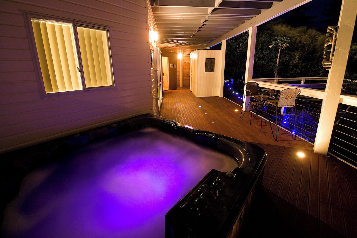 Un área de jacuzzi con terraza de madera y zona de estar cubierta.