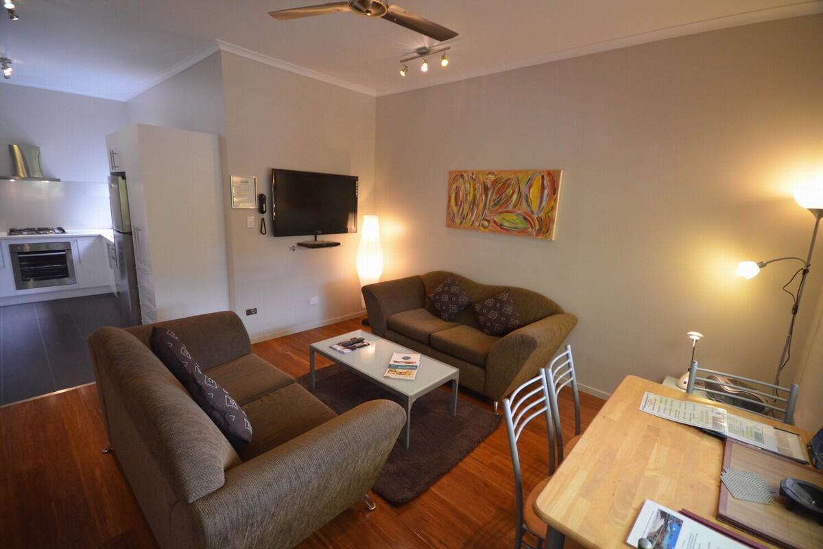 Una sala de estar con un sofá, una mesa de centro, un televisor y un cuadro en la pared.