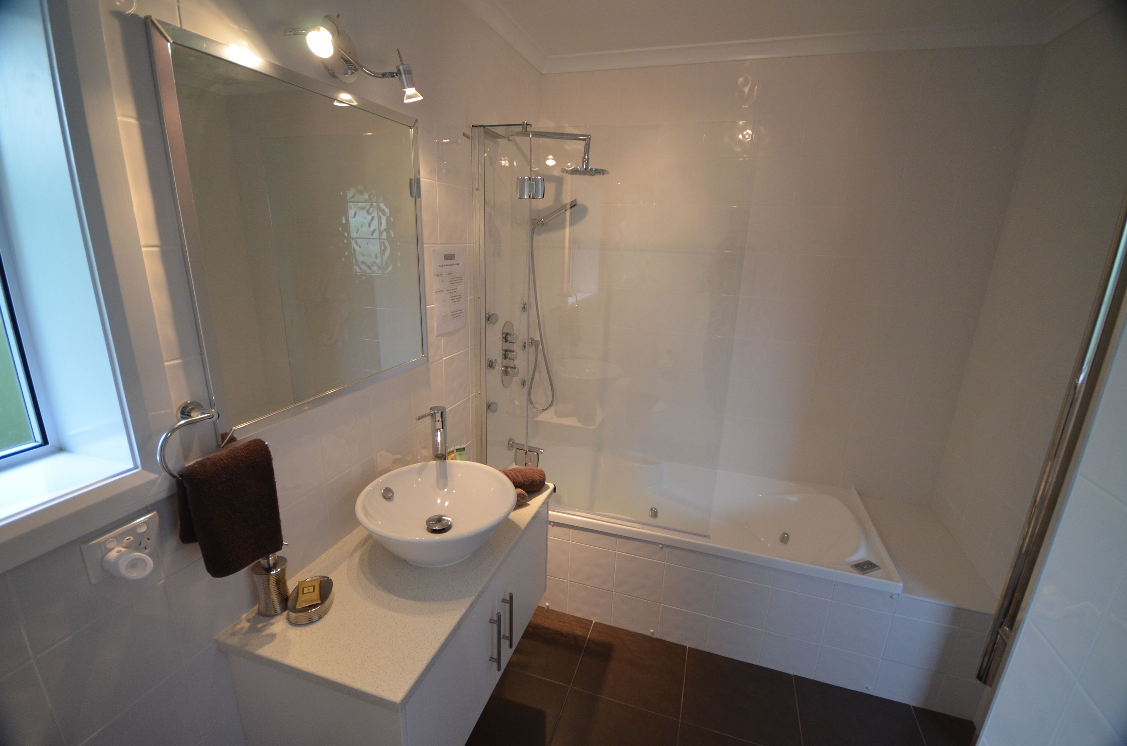 A modern bathroom with a glass-enclosed shower, a white sink, and a bathtub.