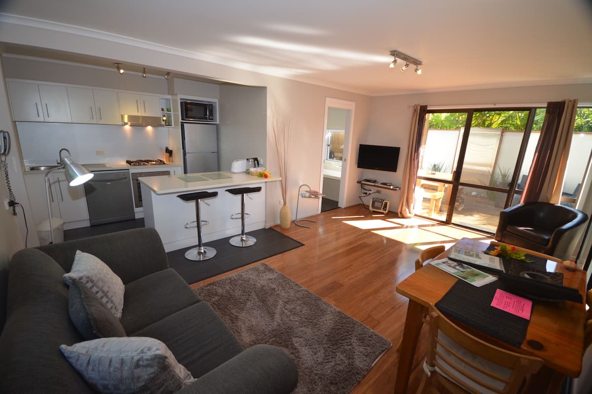 Un espacio habitable compacto con kitchenette, un sofá, una mesa de comedor y un televisor.