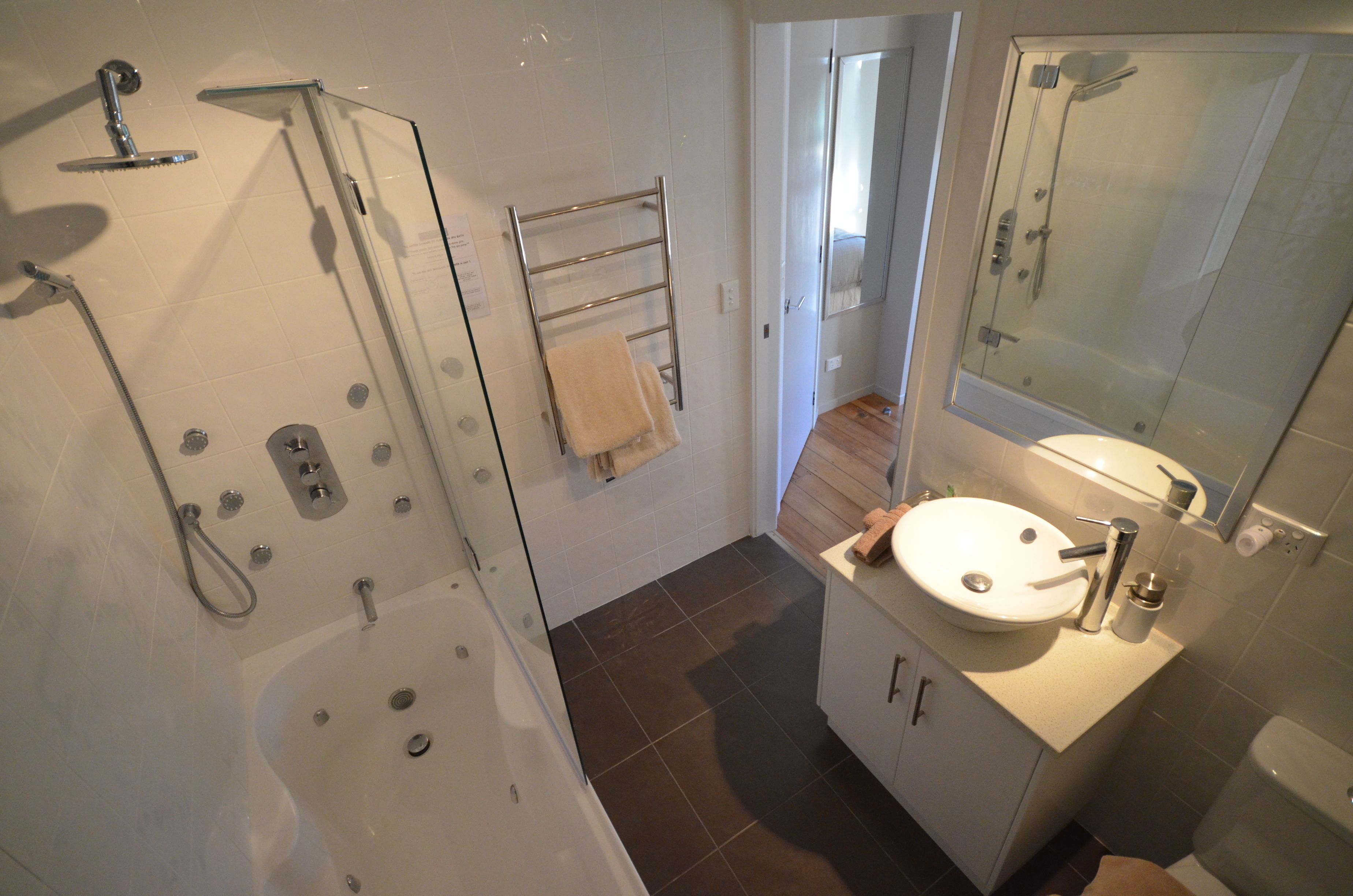 A modern bathroom with a glass-enclosed shower, a white sink, and a mirror above it.