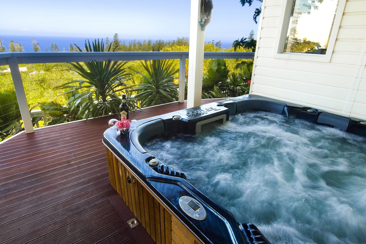 Un jacuzzi en una terraza de madera con vista al océano.