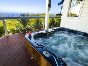 Un bain à remous sur une terrasse en bois, avec vue sur l’océan.