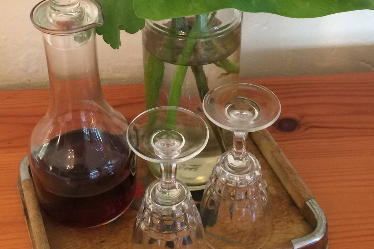 A wooden tray with a glass carafe, two crystal glasses, and a potted plant with a white flower.