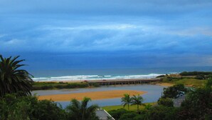 A coastal landscape with a beach, a small body of water, and a bridge connecting to the shore. - Mont Fleur B&B (Wilderness)