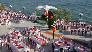 An outdoor event with round tables set up on a terrace overlooking the sea. - Atamer Hotel (Gemlik)