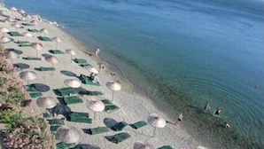 A beach with clear water, umbrellas, and people swimming. - Atamer Hotel (Gemlik)