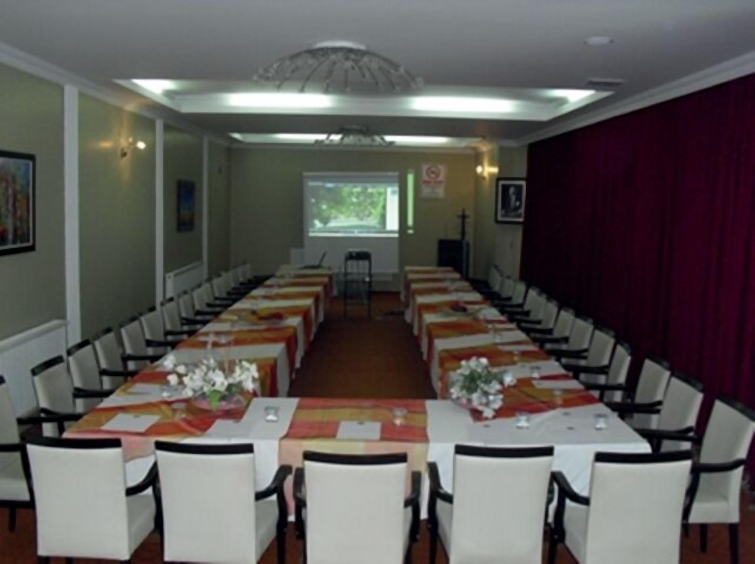 A conference room with long tables and chairs, a large window, and a red curtain.