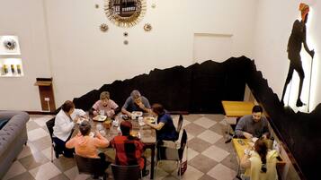 Un comedor con un grupo de personas sentadas alrededor de una mesa, un elemento decorativo en una pared negra y un ventanal con vistas.