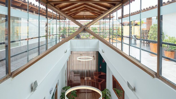 A spacious atrium with a high ceiling, wooden beams, large windows, and a central circular light fixture. - Maytaq Wasin Hotel (Cusco)