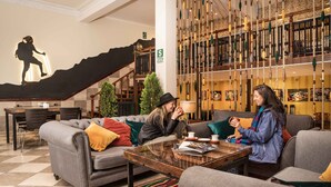 A lobby with a staircase, a seating area with sofas, a coffee table, and a wall with a climbing figure. - Maytaq Wasin Hotel (Cusco)