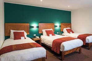 A hotel room with three beds, each with a wooden headboard, white bedding, and red throw pillows. There are bedside lamps and a telephone on the nightstands. - Maytaq Wasin Hotel (Cusco)