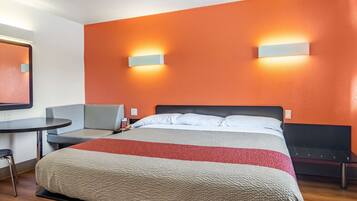 A hotel room with a bed, a desk, and a chair.