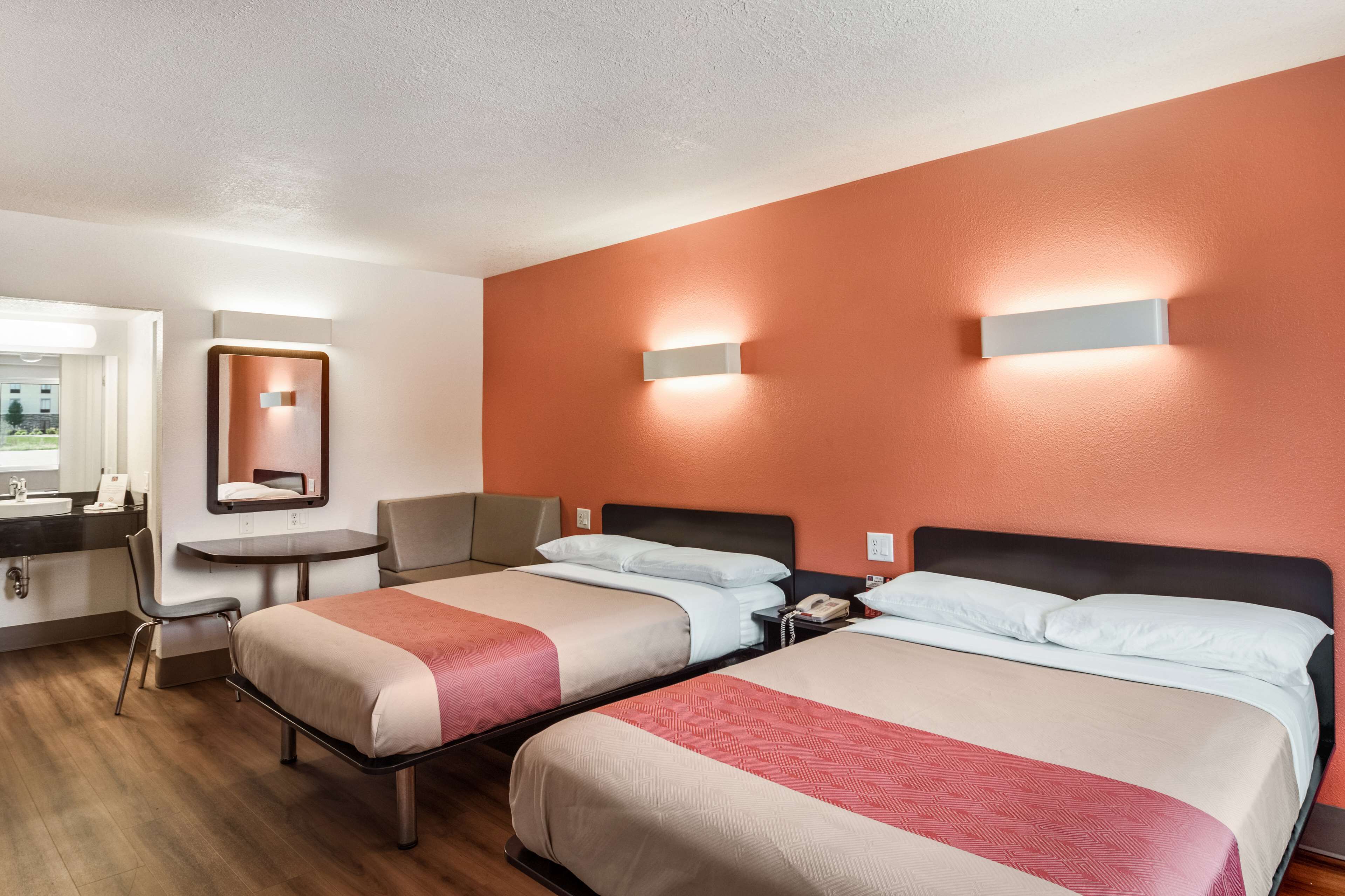 Una habitación de hotel con dos camas, un escritorio, una silla y un baño.