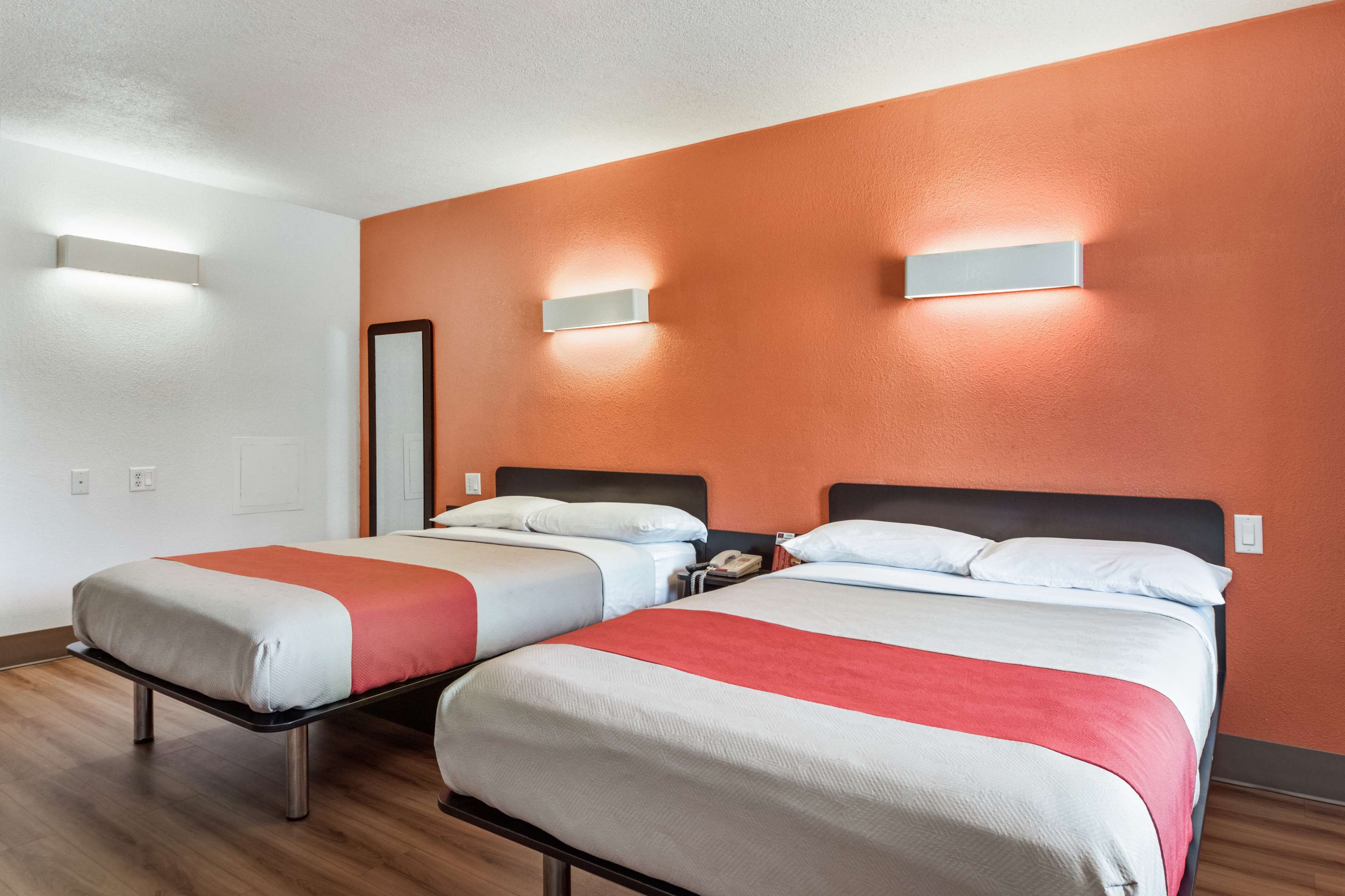 Une chambre d ’hôtel avec deux lits, chacun recouvert d’une courtepointe blanche et rouge, et dotée d’un plancher en bois.