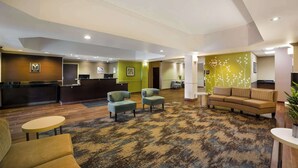 A lobby with a reception desk, seating area, and a green wall with a floral design.