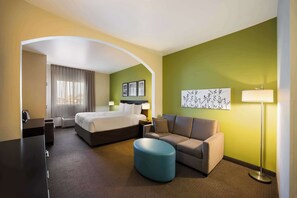 A hotel room with a bed, a sofa, a desk, and a lamp. - Sleep Inn & Suites Colby (Colby)